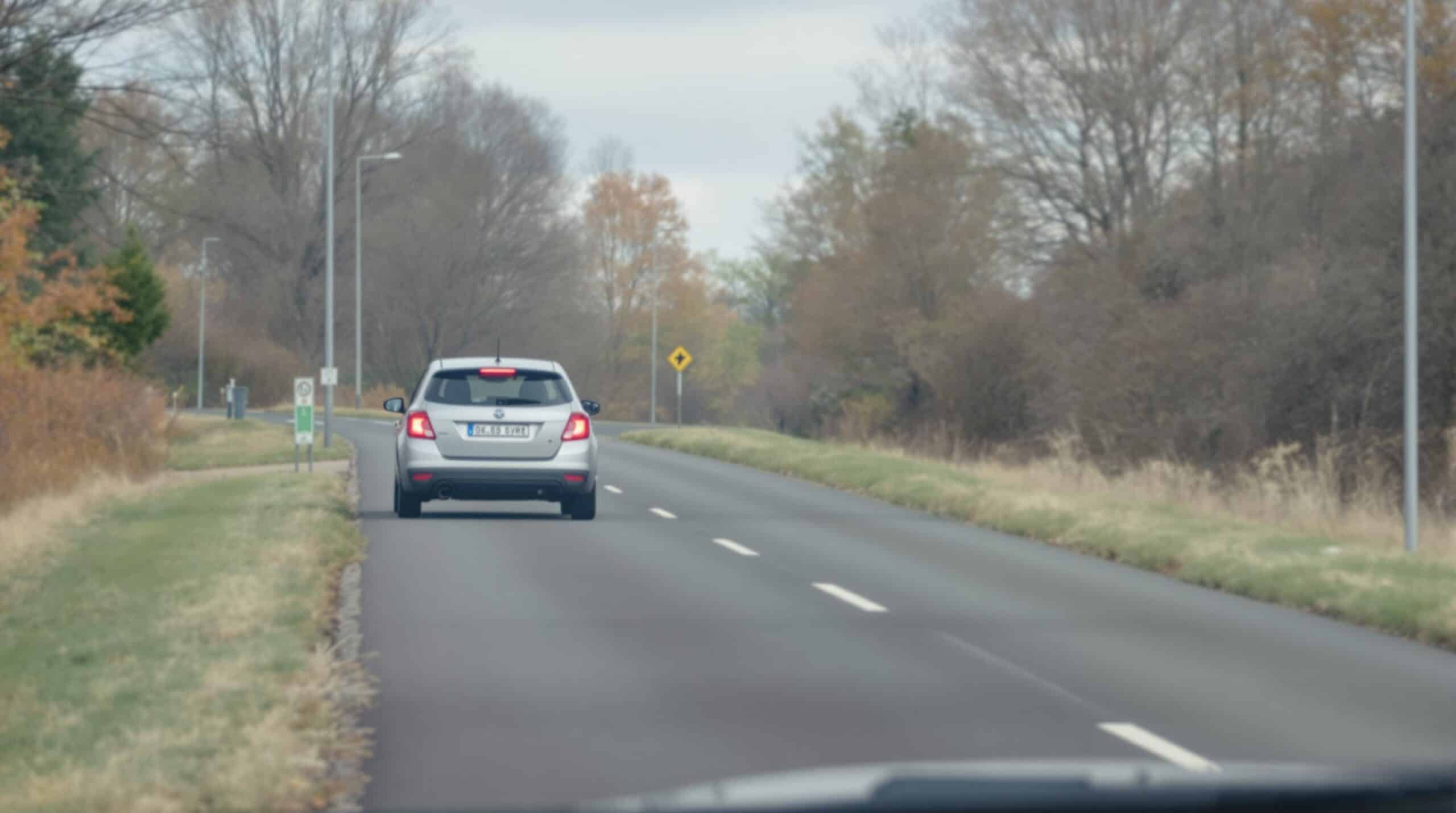 Een zakelijke auto rijdt voorzichtig op een natte, gladde weg.
