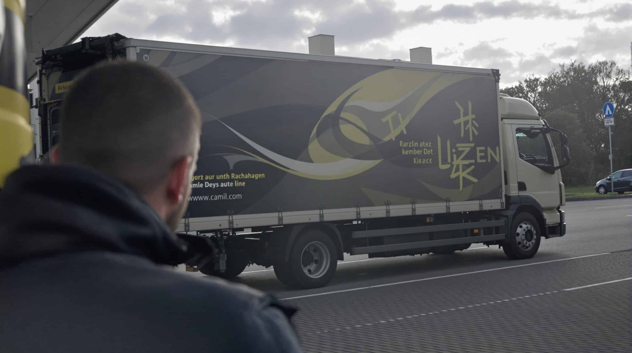 Een man kijkt in de open laadruimte van een grote bestelwagen op een parkeerplaats.
